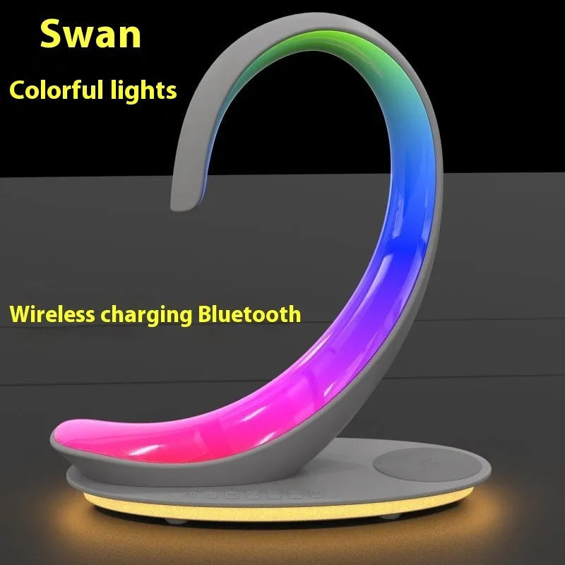 White swan-shaped desktop device with wireless charging pad, Bluetooth speaker, and colourful atmosphere lighting.