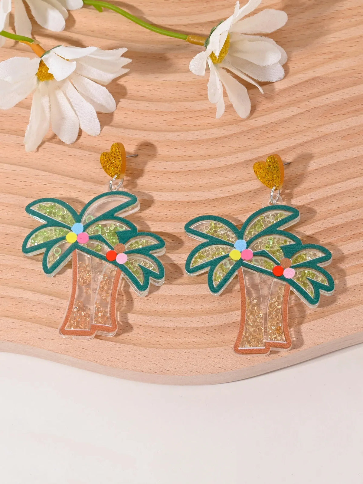 A pair of colourful acrylic earrings with a cake design next to other fruit and ice cream style earrings.