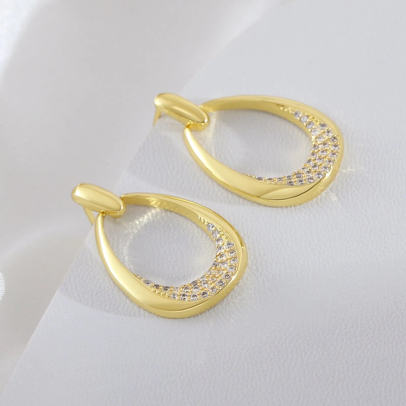 Yellow gold geometric drop earrings with round and oval ring elements on white background