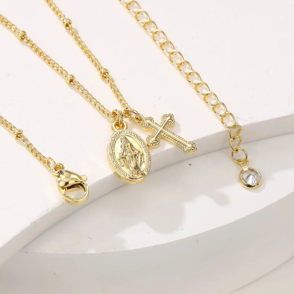 Gold coloured geometric cross Virgin Mary pendant necklace on a chain.