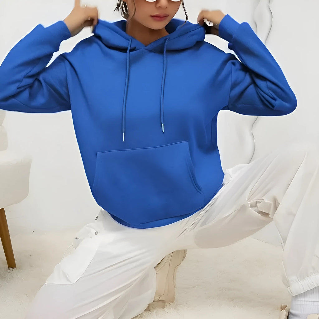 Woman wearing a loose grey sweatshirt with a front pocket and drawstring hem.