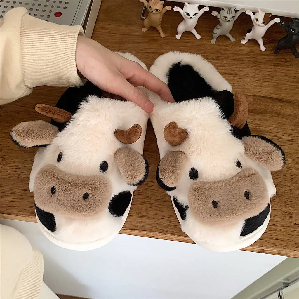 White plush cow slippers for women with black spots, a smiling face, and a textured non-slip sole.