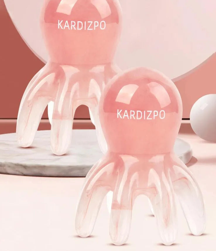 Pink octopus-shaped facial massage comb with dual-pronged tip for periocular pressure points