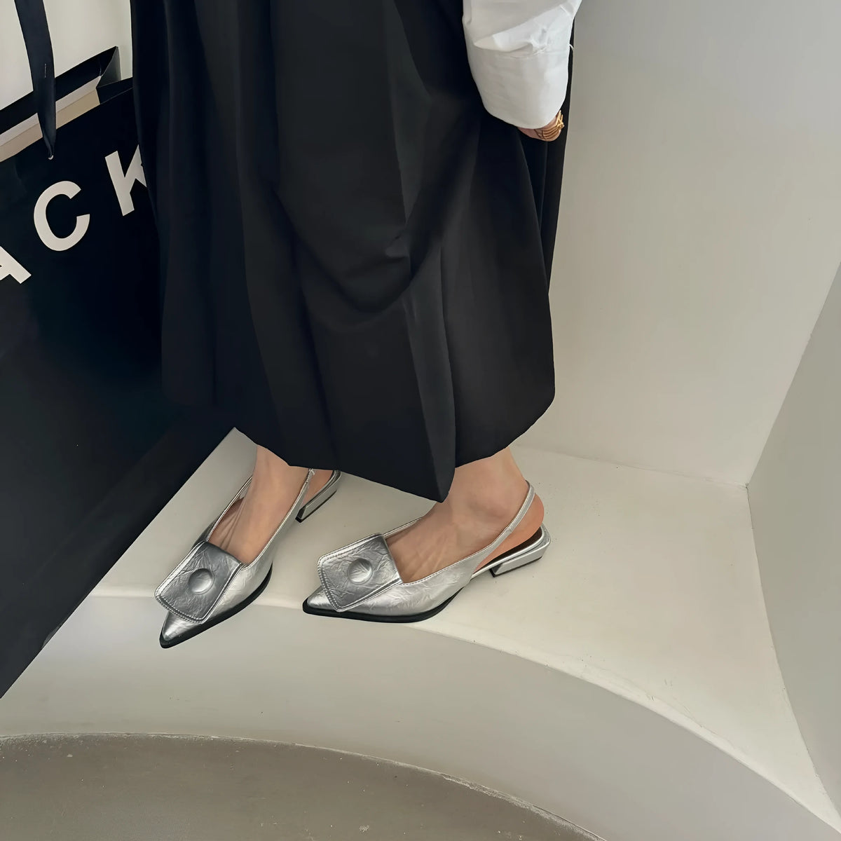 Women's low heel pointed toe sandals with a back strap in black, shown from the side.