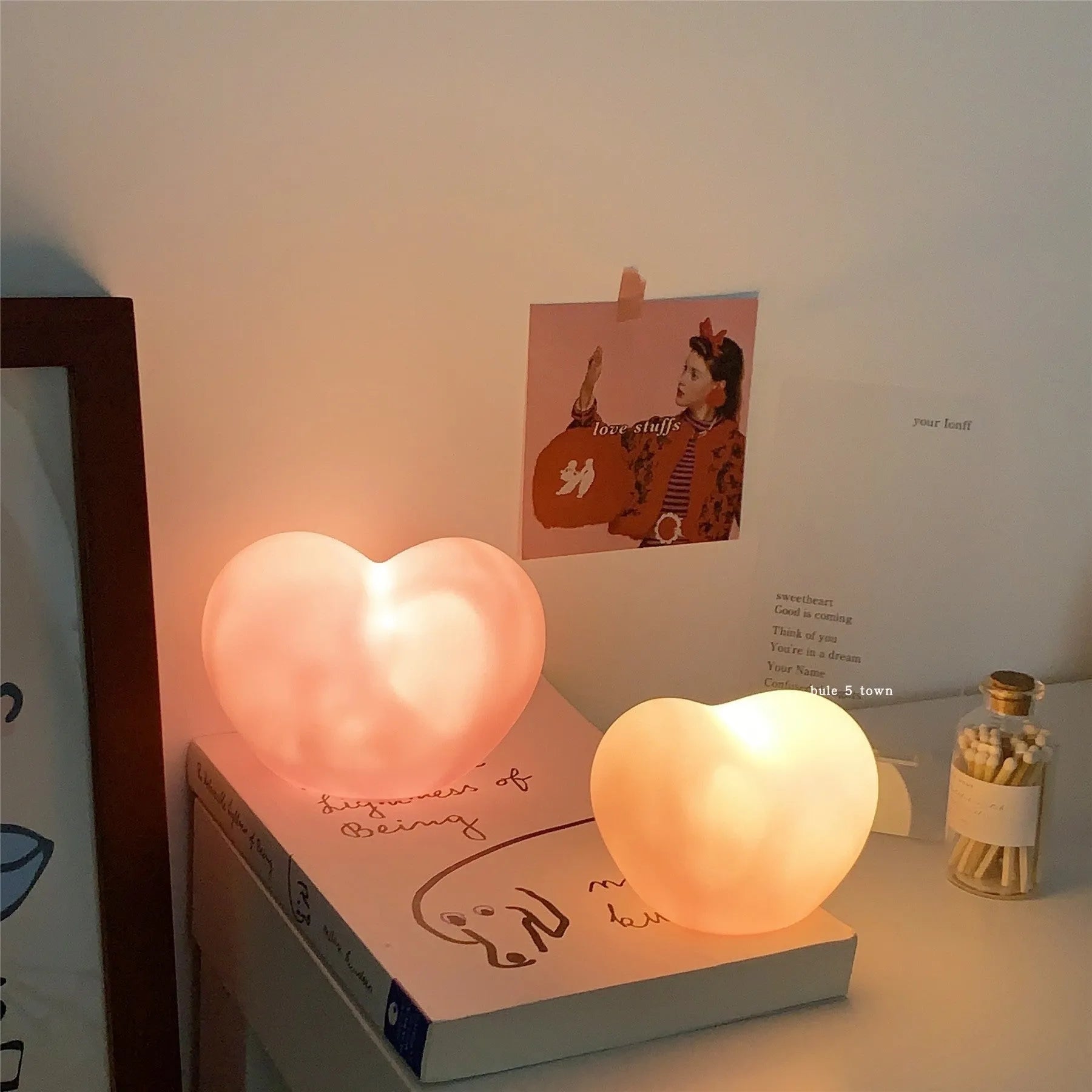 White and pink vinyl love-shaped atmosphere lamps in two sizes on a shelf.