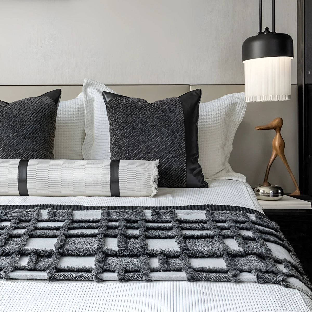 Grey and white plaid bed runner blanket with matching pillowcase and round leather-look pillow on a bed.