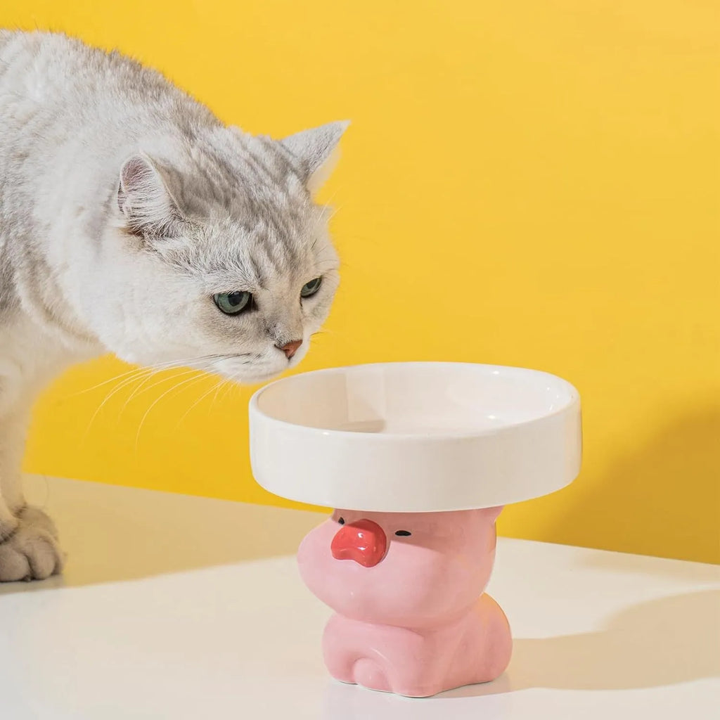 Raised ceramic cat bowl with cute animal design in pink, yellow, or white on a white background