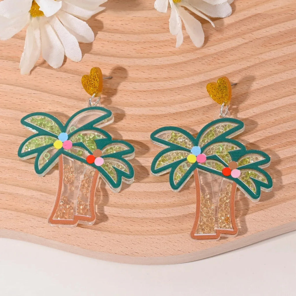 A pair of colourful acrylic earrings with a cake design next to other fruit and ice cream style earrings.