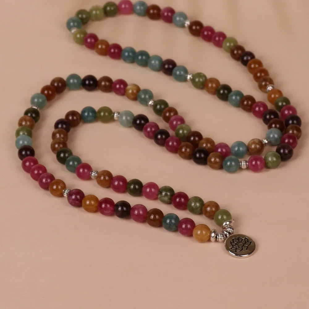 Close-up of a multi-layer beaded bracelet with 108 beads and a hanging lotus charm, made from alloy and tourmaline-coloured material.