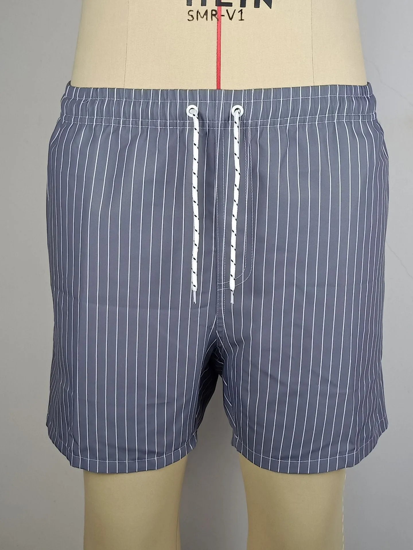 Men's striped polyester beach shorts in grey, shown with a straight leg fit and triangle lining detail.
