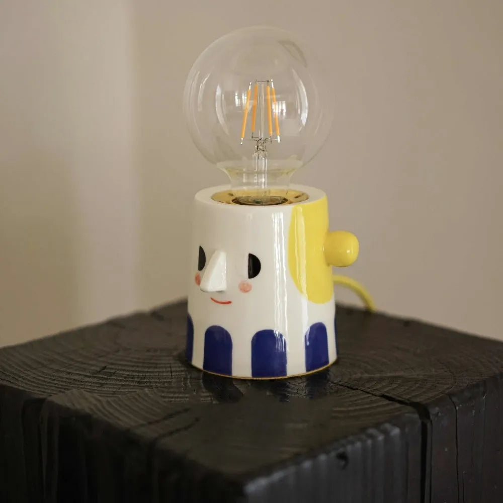 Handmade ceramic ball headlight bedside lamp on a table.