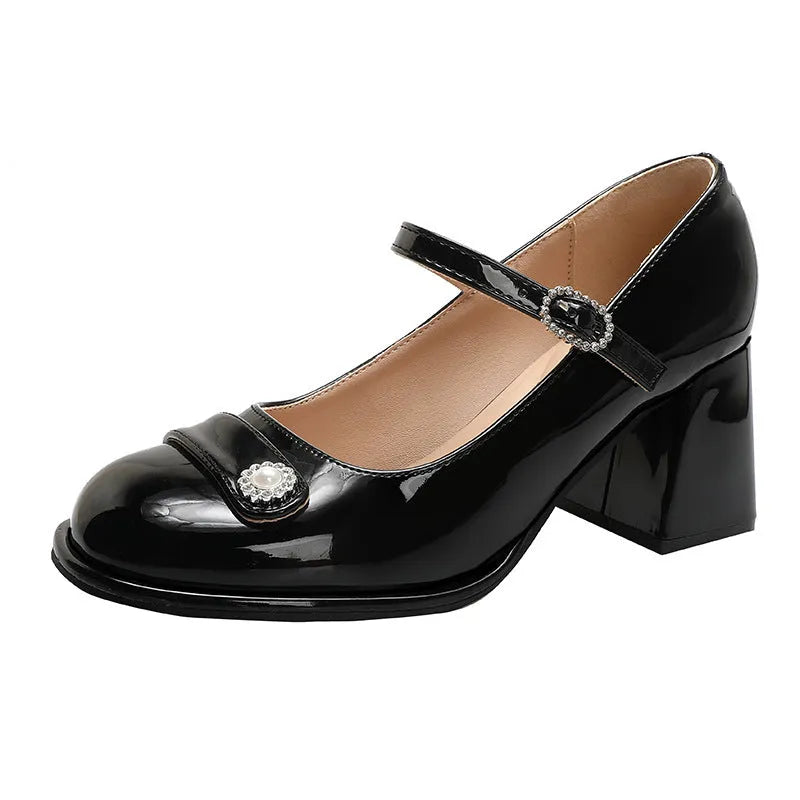 Women's black patent leather round toe high heels with a chunky heel and buckle strap, shown on a foot.