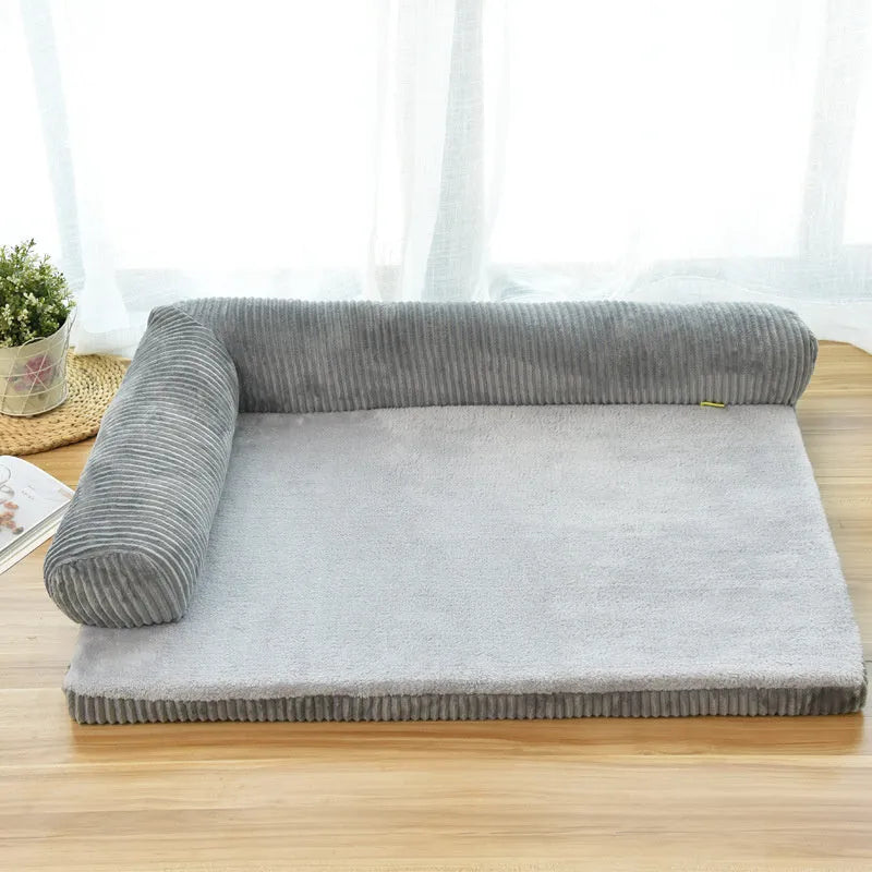 Corduroy pet sofa dog bed with a raised bolster, shown in a grey colour on a wooden floor.