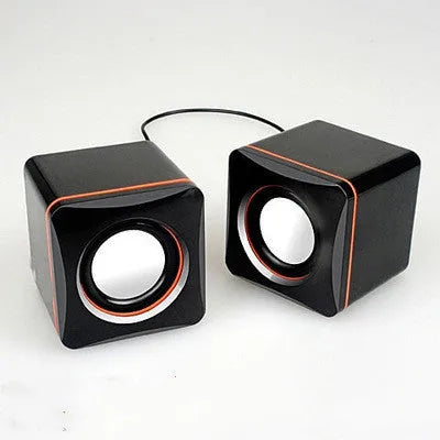 Small black square USB-powered computer speaker with audio and USB cables