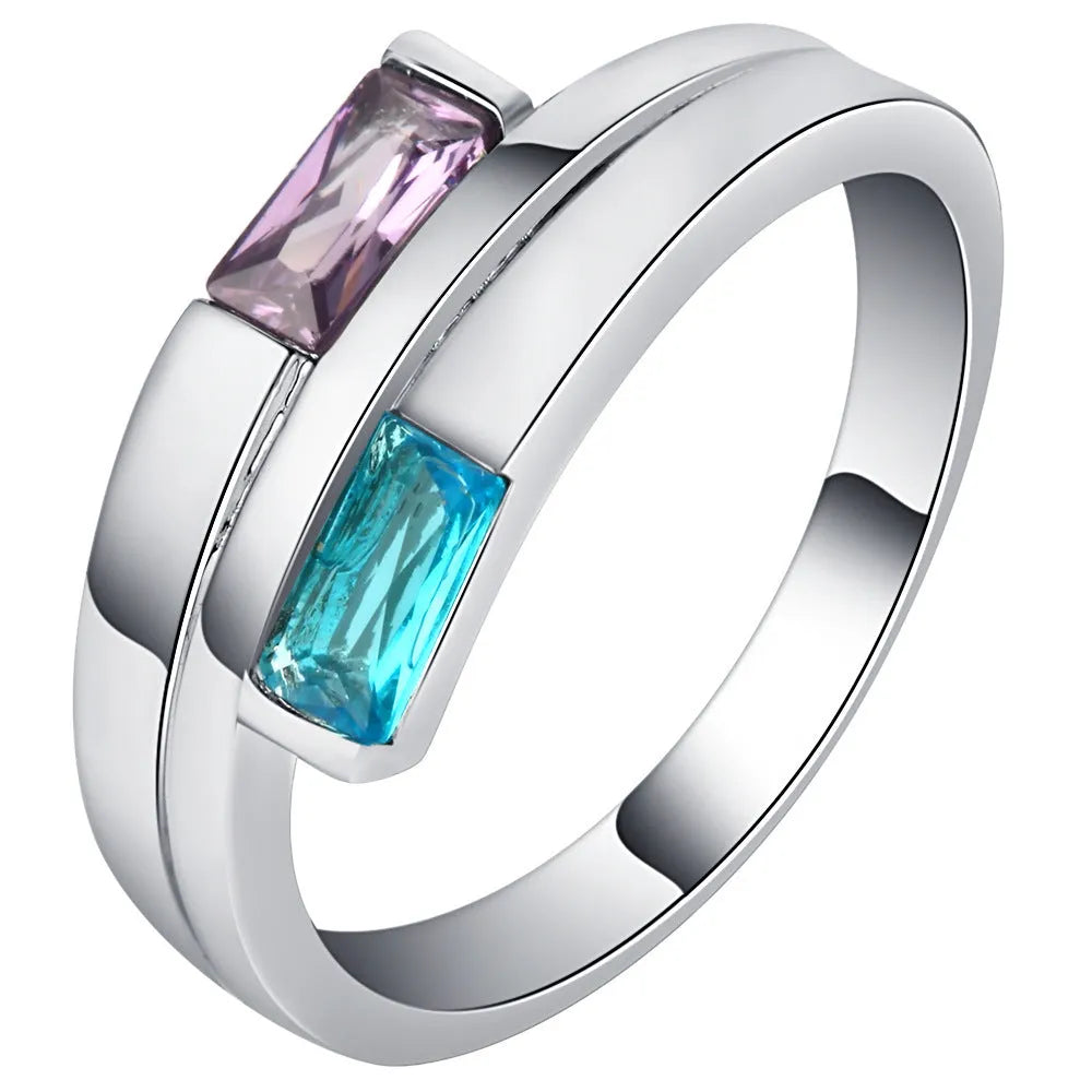 Silver coloured electroplated copper ring with a central inlaid zircon stone on a plain background.