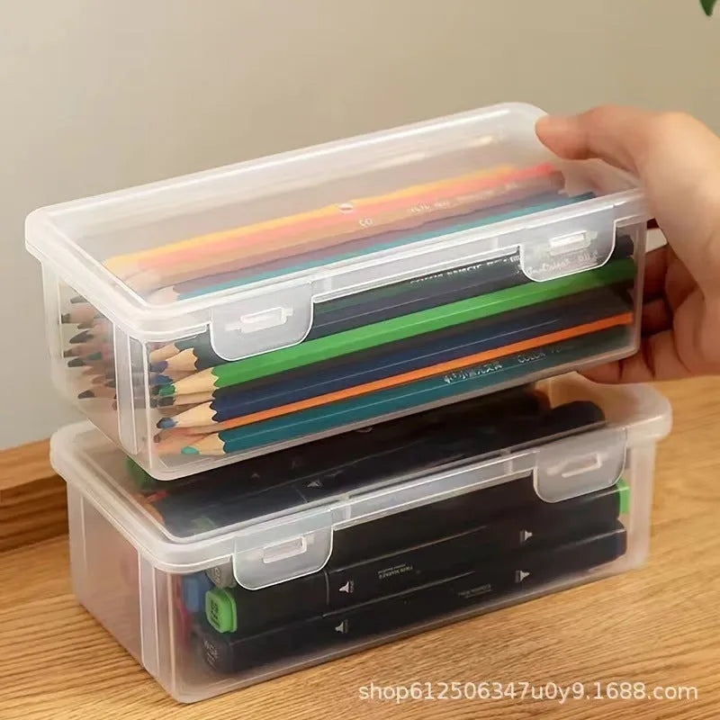 Transparent plastic stationery storage box containing pencils, colour leads, and art supplies