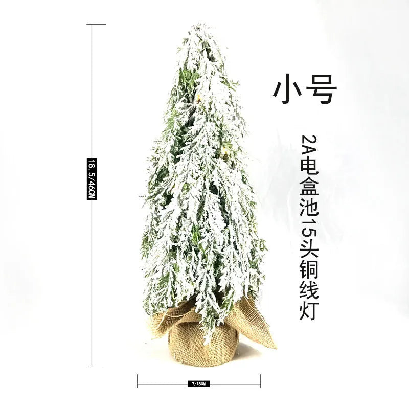 Small white 24-inch plastic Christmas tree with LED lights and simulated snow spray on desktop