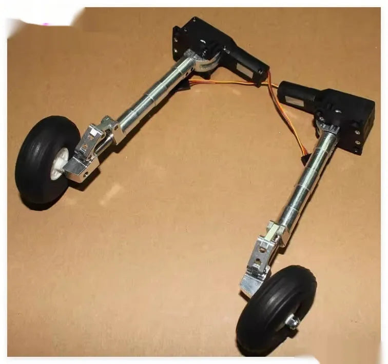 Retractable alloy landing gear with wheels for toy aircraft, shown in inclined kneeling shock-absorbing position.