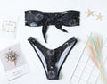 Black printed one-piece swimsuit with backless design on a mannequin.