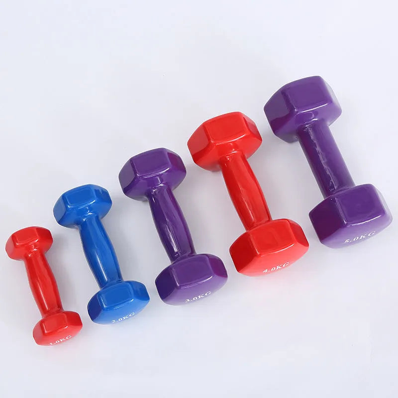 Set of bright green and purple plastic dumbbells on a wooden floor.