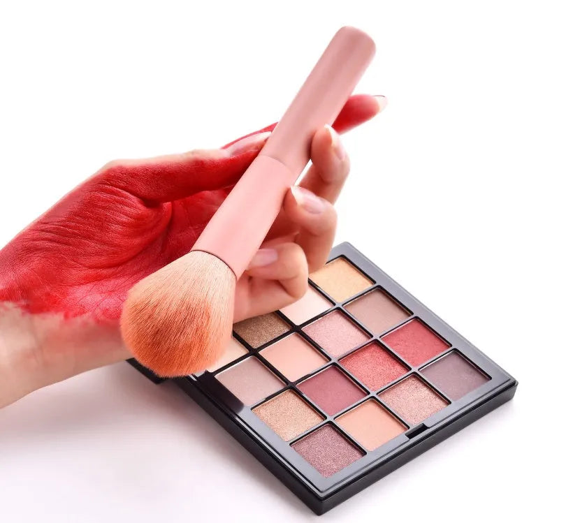 Ten wooden-handle make-up brushes for face and eye application in a pink travel case.