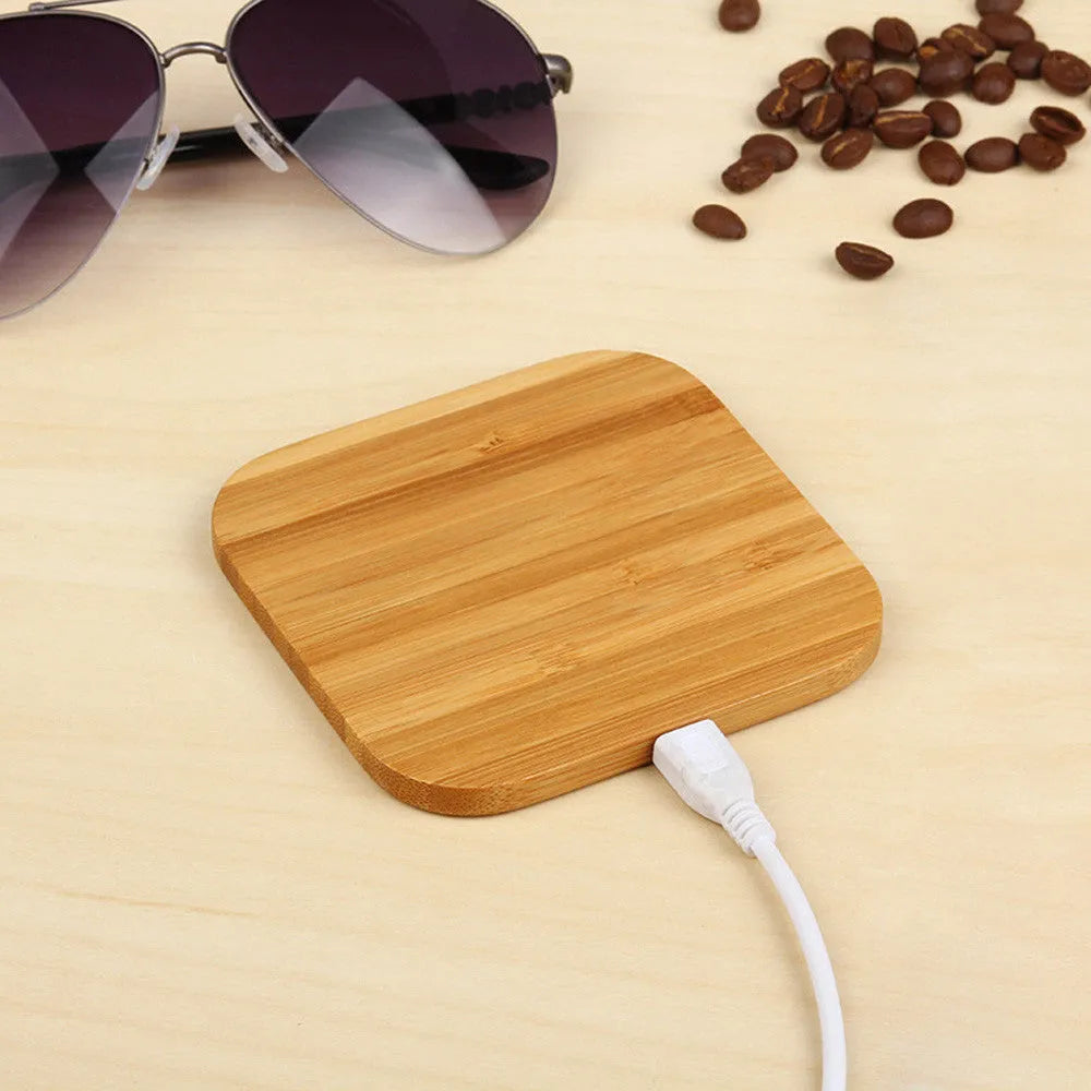 Square brown wooden bamboo 5W Qi wireless charging pad on a table.
