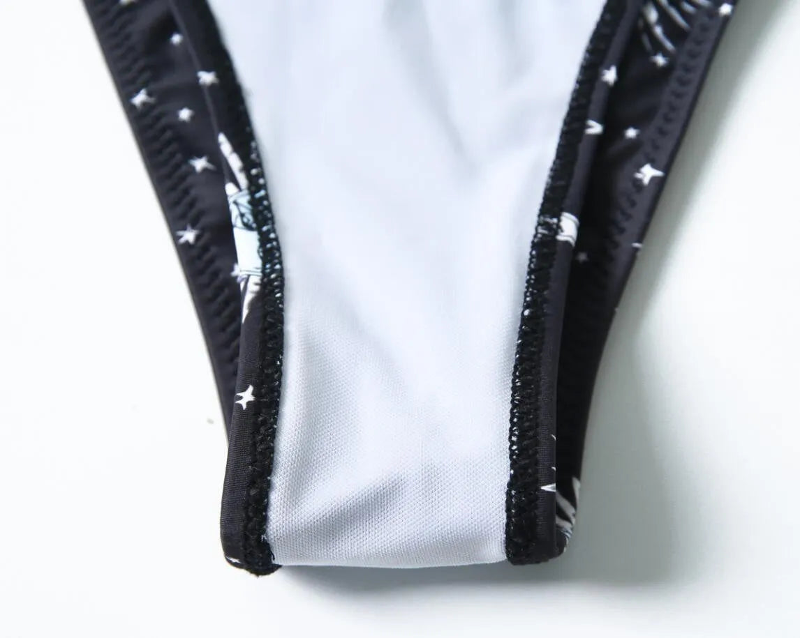 Black printed one-piece swimsuit with backless design on a mannequin.