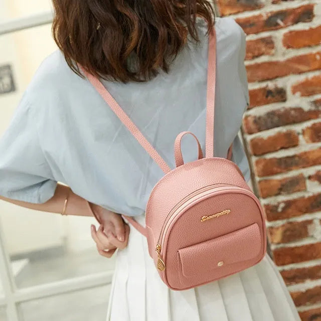 Small black PU leather women's shoulder backpack worn as a backpack, showing zipper closure and compact size.