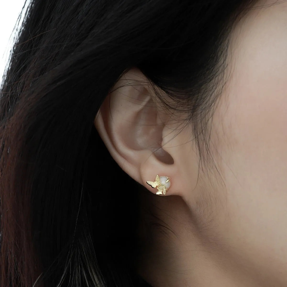 Close-up of 925 silver butterfly stud earrings with animal detail in gold tone finish.
