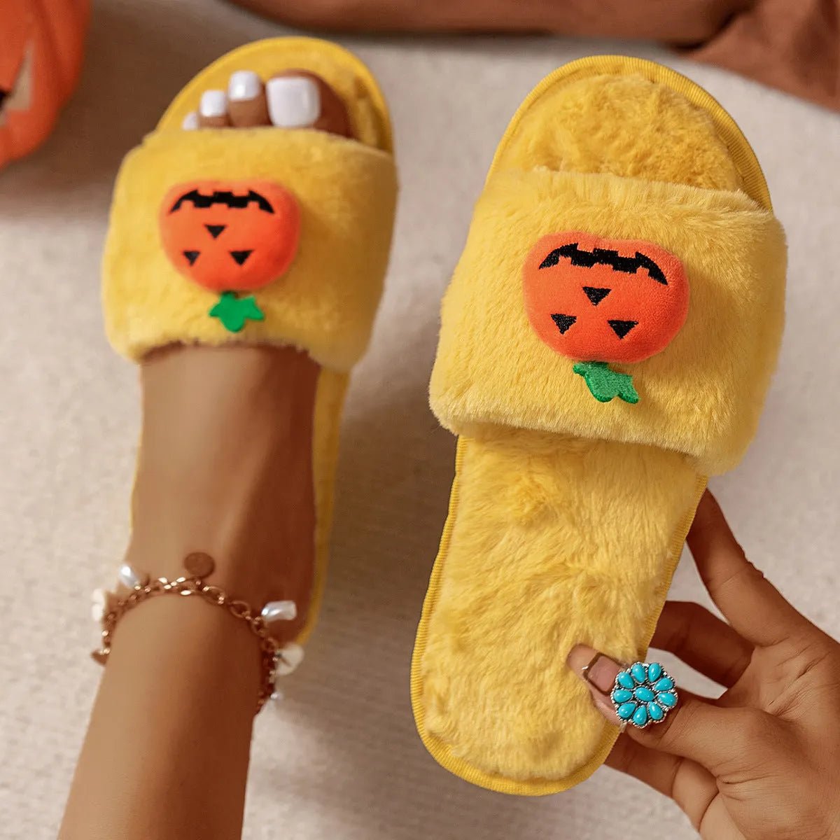 Yellow pumpkin plush open-toe slippers with a cartoon face, shown on a white background.