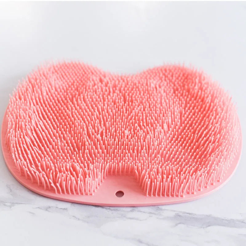Orange silicone bristle massage bath brush with suction cup bottom on bathroom floor
