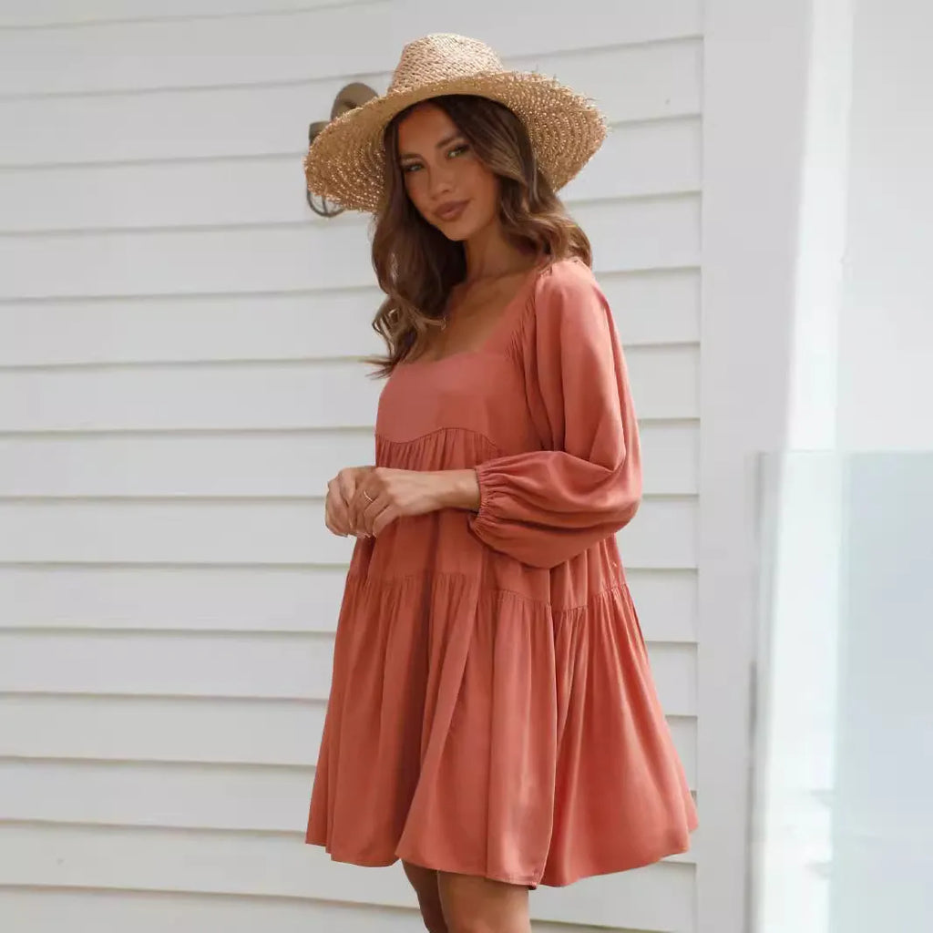 Orange backless children's dress with a square collar and puff sleeves on a mannequin.