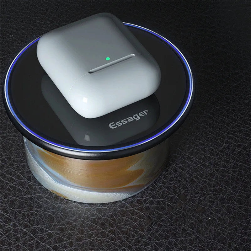Black Qi fast wireless charging pad on a desk next to a smartphone, showing a blue LED charging indicator light.