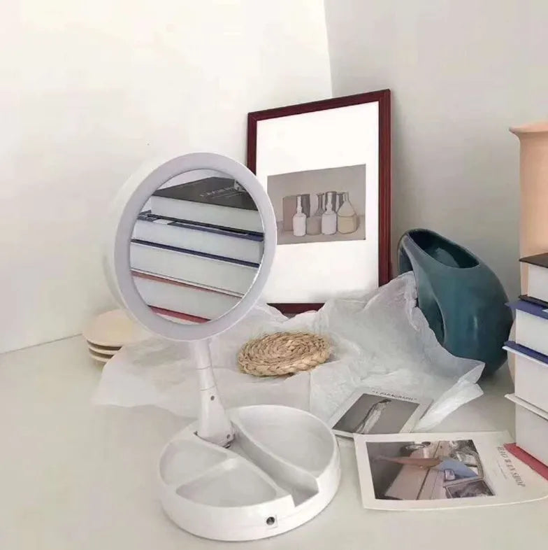White acrylic foldable LED vanity mirror with USB charging port and double-sided design on a table