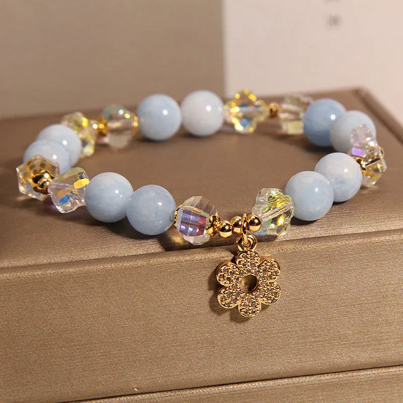 Aquamarine crystal bracelet with a four-leaf clover charm and a pearl decorative element on a wrist.