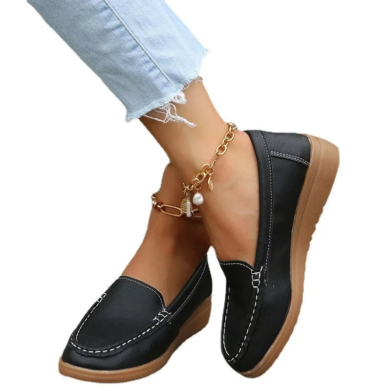 Women's flat slip-on loafers in PU leather with car suture detailing on the upper.