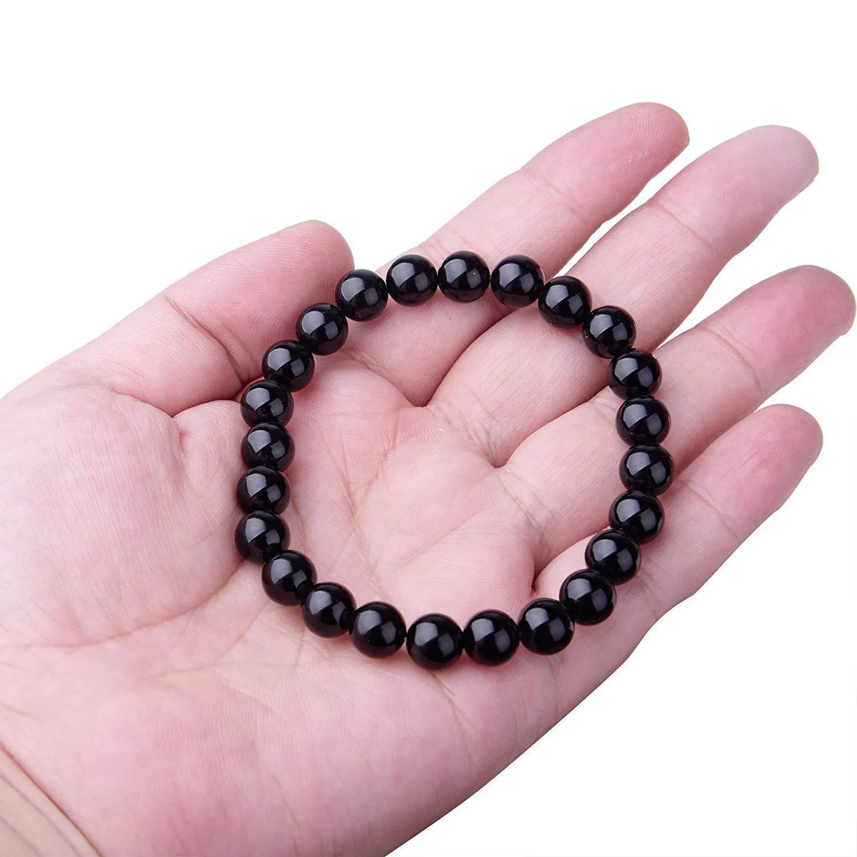 Close-up of a women's black onyx bracelet with 8mm geometric agate beads on a black elastic cord.