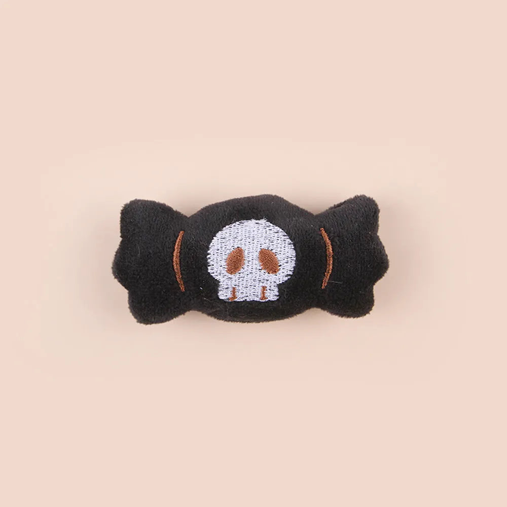 Small plush cat teaser toy in candy, eyes, and skull designs on a blue background.