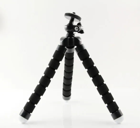 Black flexible octopus tripod with bent legs holding a smartphone on a table.