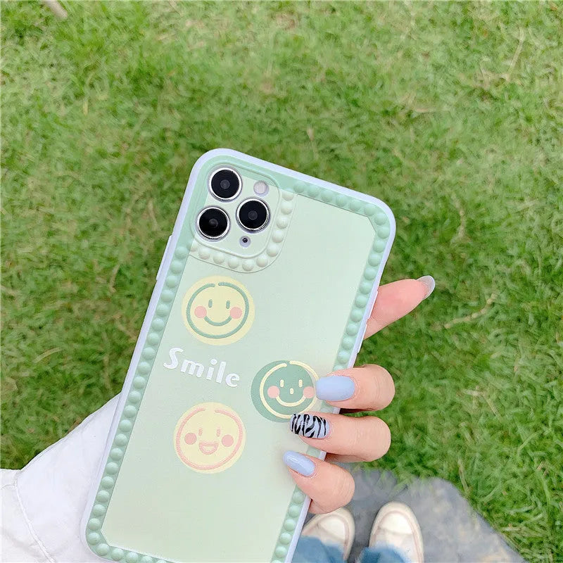 Green TPU iPhone case with smiley face and geometric pattern inside a polka dot frame.