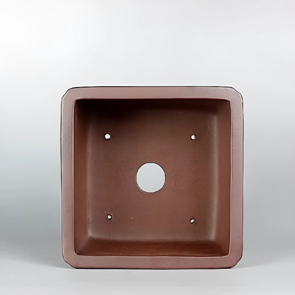 Handmade brown antique purple clay flower pot for plants on a windowsill.