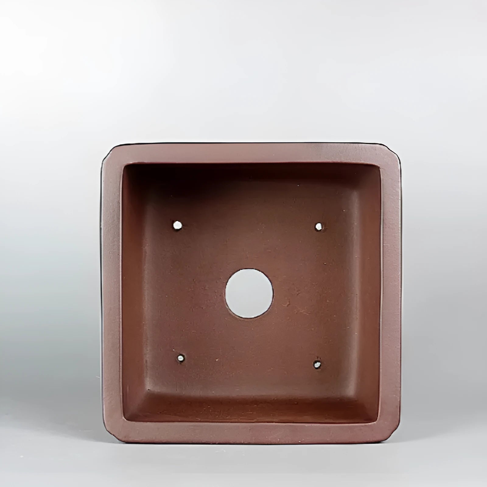 Handmade brown antique purple clay flower pot for plants on a windowsill.