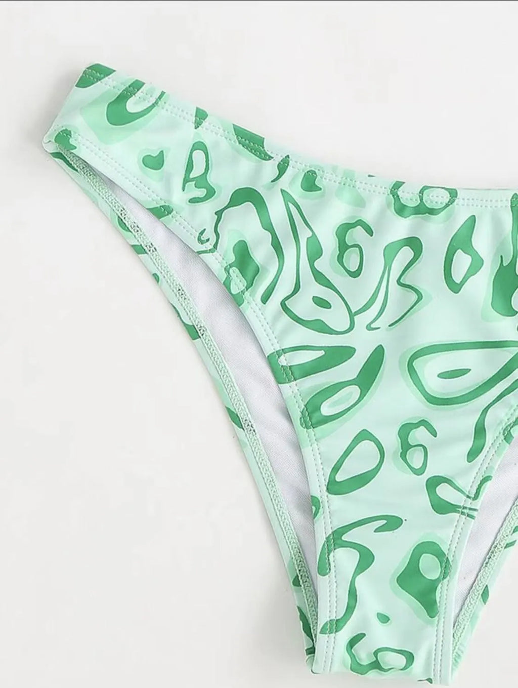 Green floral bandeau bikini swimsuit set with briefs on a neutral background.