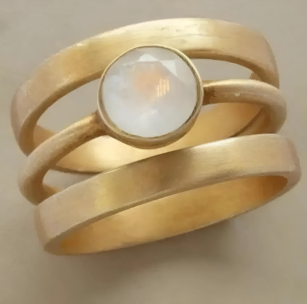 A gold-plated geometric ring with a micro-inlaid white chalcedony stone on a titanium steel band.