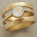 A gold-plated geometric ring with a micro-inlaid white chalcedony stone on a titanium steel band.