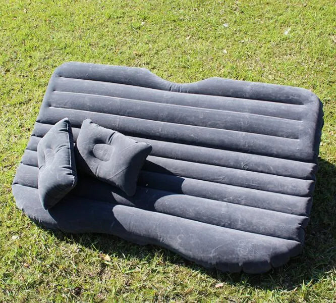 Black inflatable car bed with flocked texture, shown with two pillows inside a car.