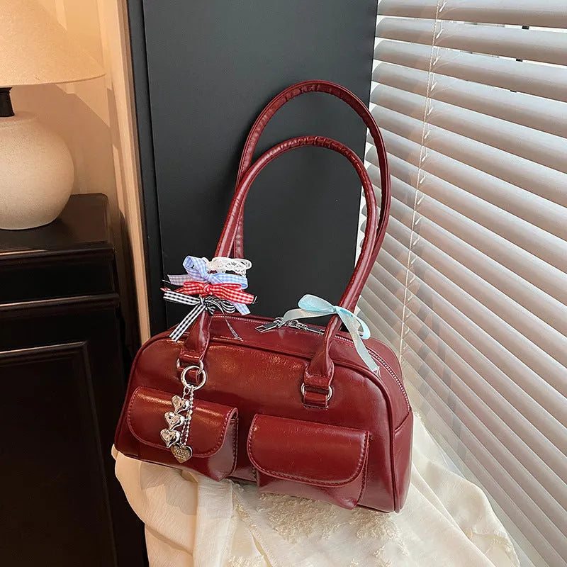 Women's black PU leather retro pillow handbag with double shoulder straps shown carried underarm