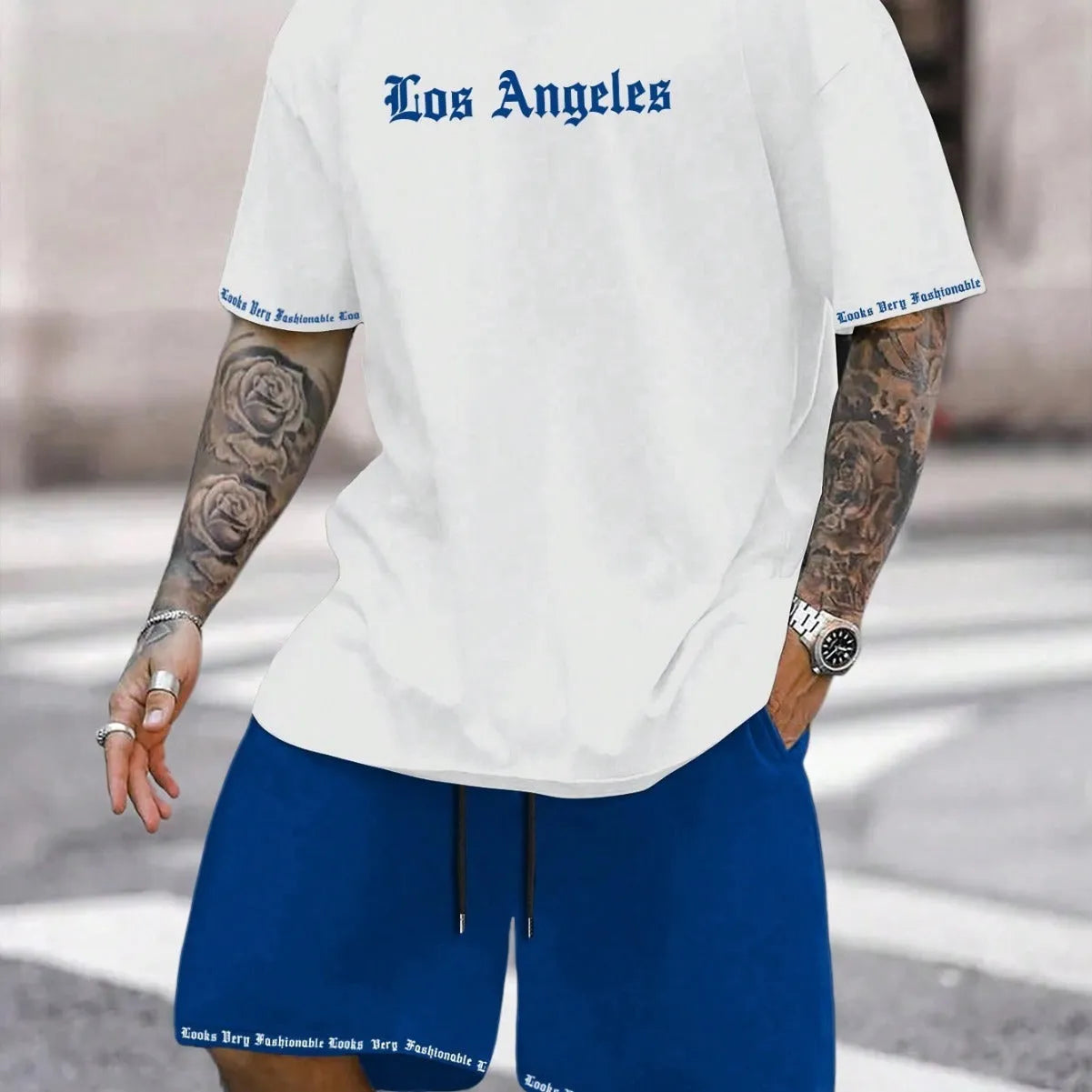 Man wearing a blue printed short-sleeved top and matching shorts from a sports-style two-piece set