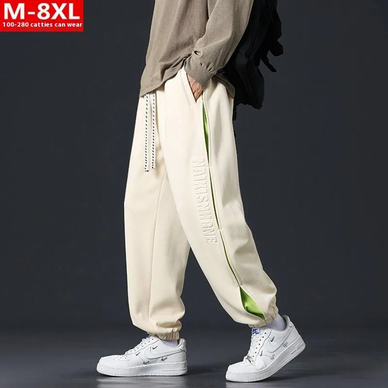 Man wearing grey green loose-fit cotton trousers with stitching print detail and an ankle band.