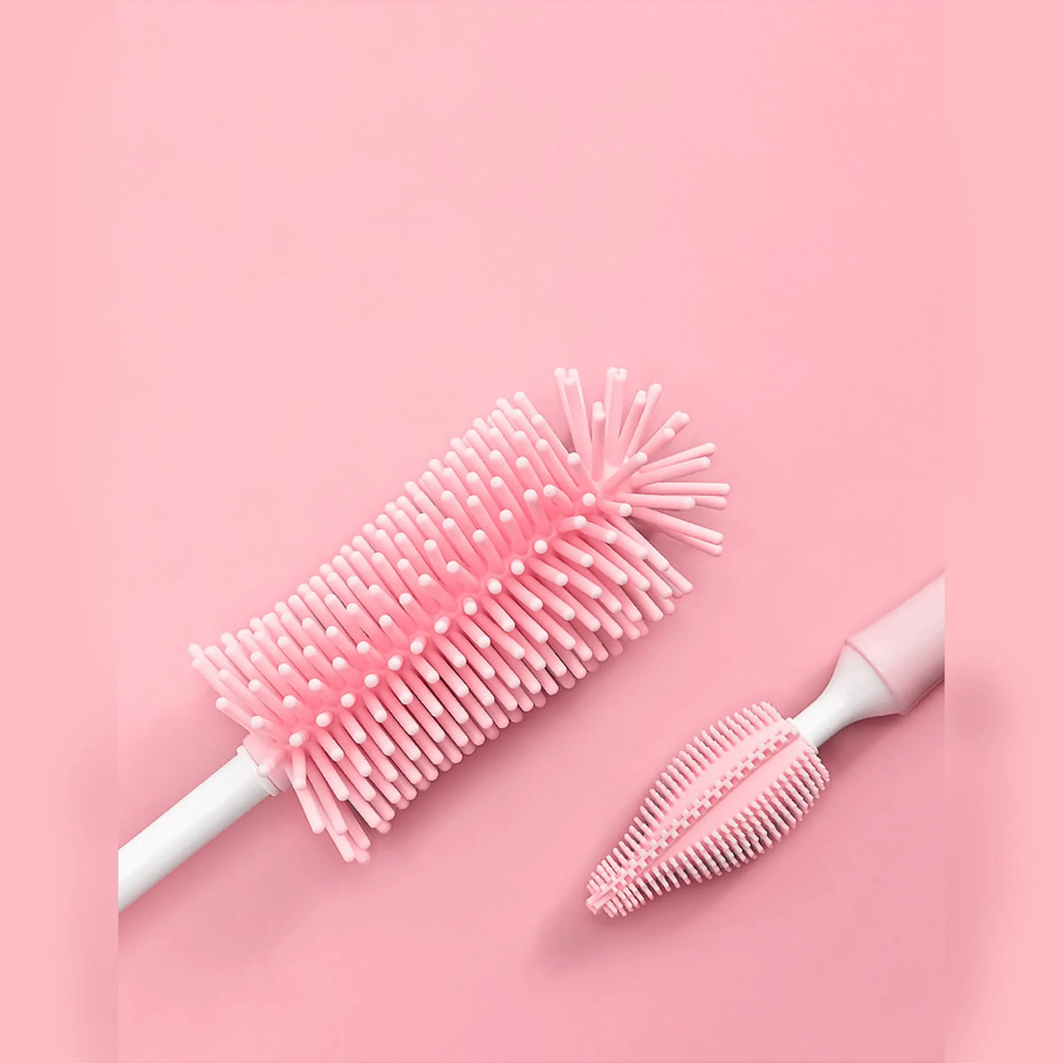 Silicone baby bottle brush with straw cleaning attachment in pink, blue, and yellow colours